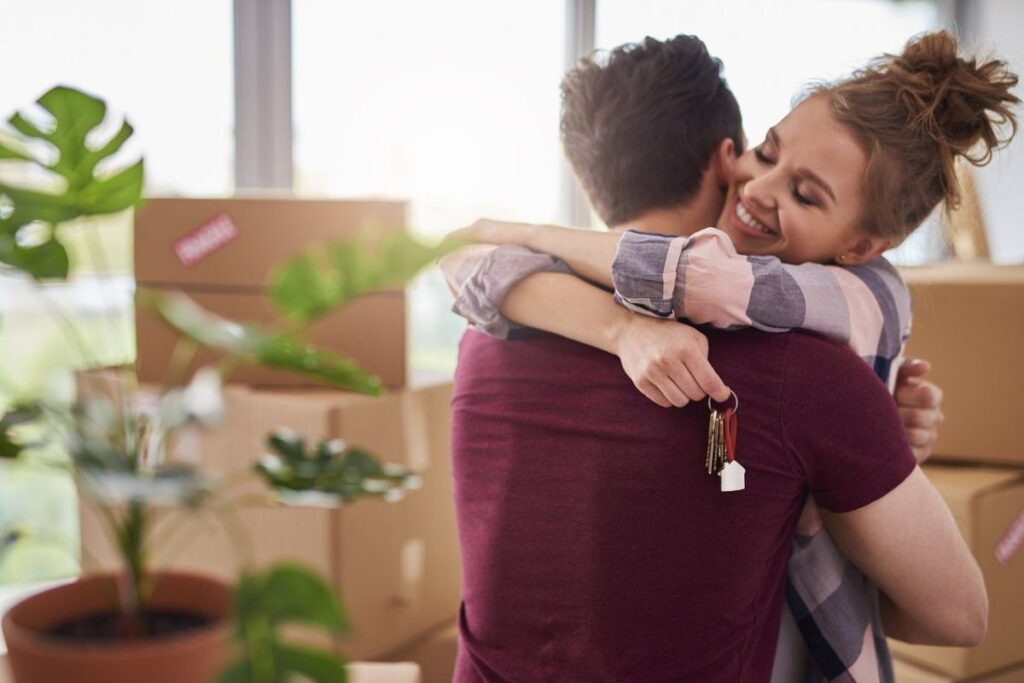 uomo e donna che si abbracciano in una stanza piena di scatoloni