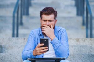 Uomo perplesso mentre guarda lo smartphone