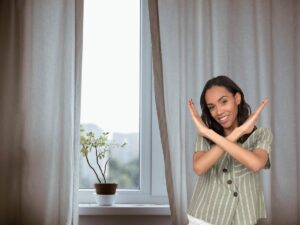 finestra con tendaggio lungo e donna che fa segno di no