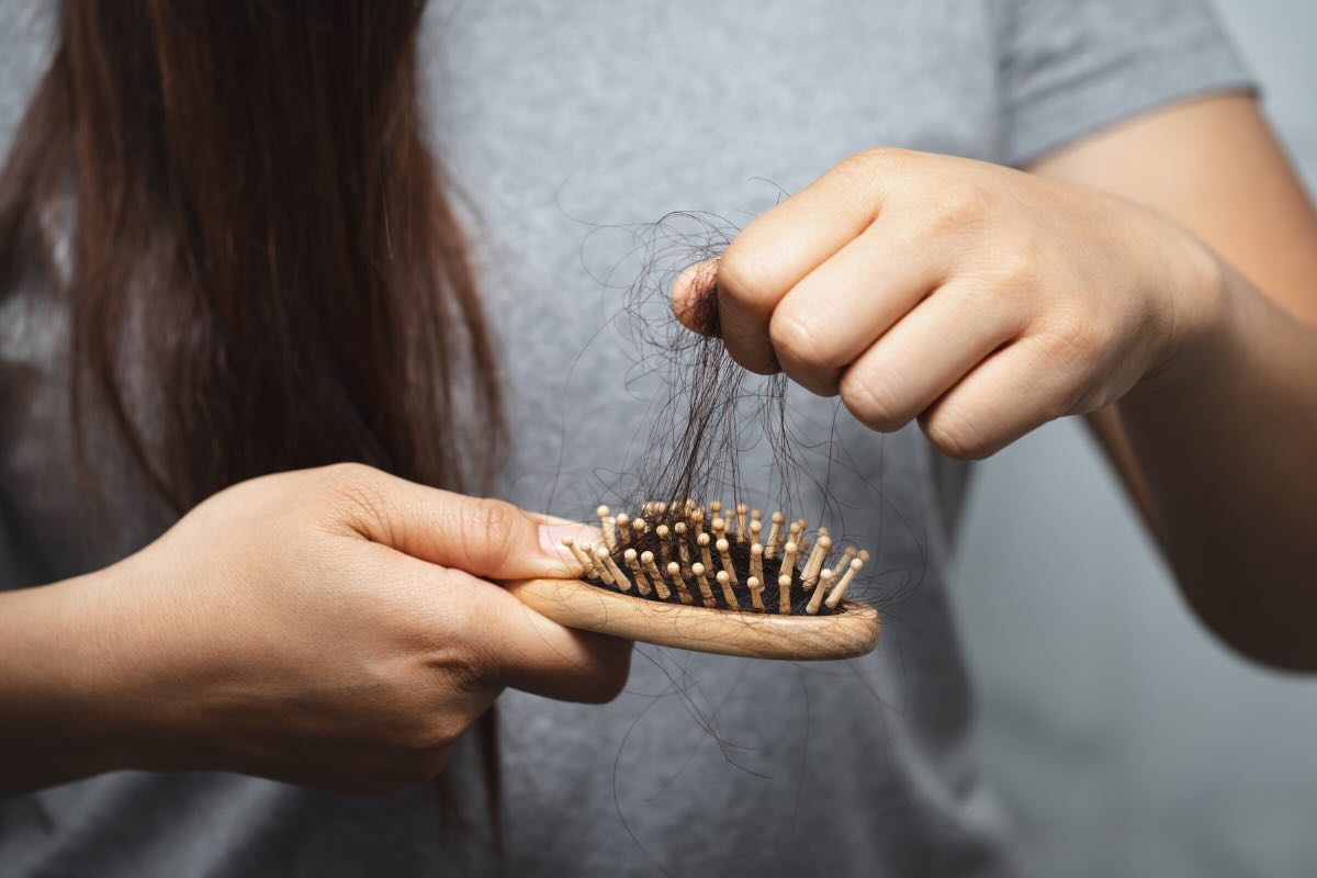 mani che tolgono capelli dalla spazzola