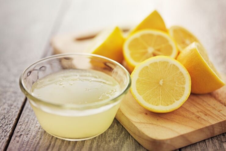 Ciotola con succo di limone, limoni sul tagliere