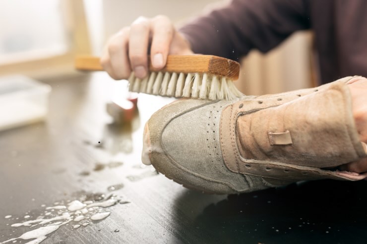 mano con spazzola che strofina su scarpe da ginnastica