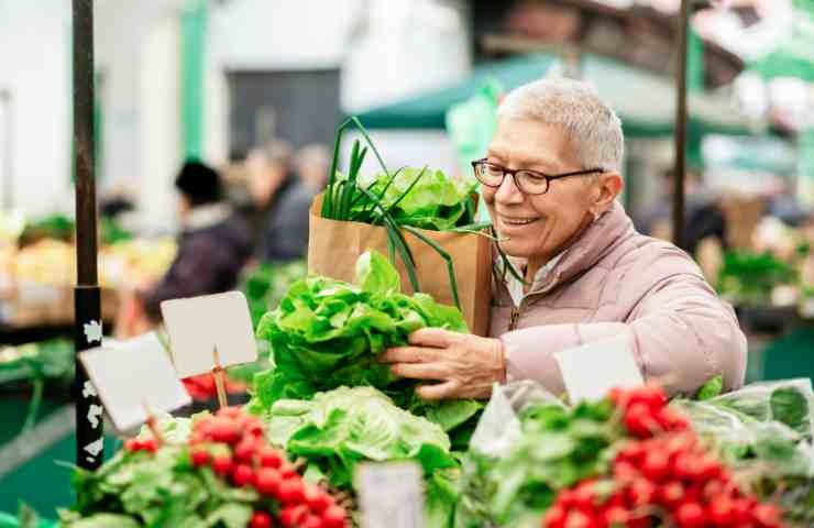 Donna fa la spesa nel reparto verdure