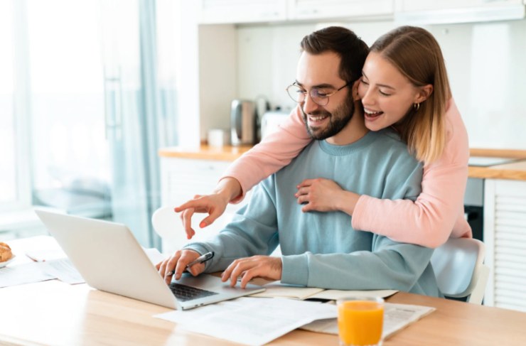 uomo e donna che sorridono felici davanti al computer