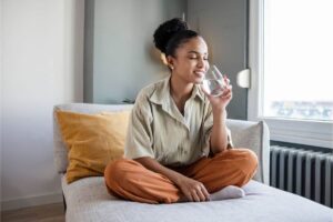 Ragazza seduta sul letto felice beve da bicchiere