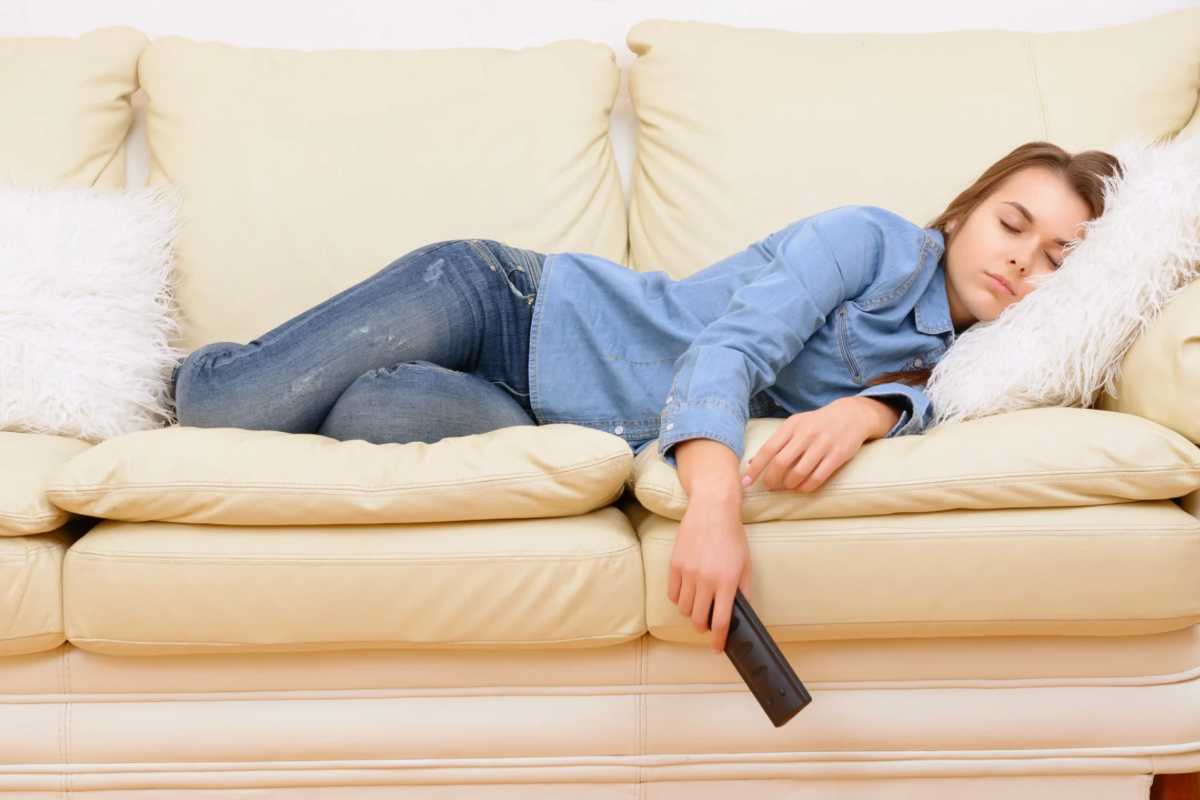 Donna che dorme sul divano con telecomando in mano