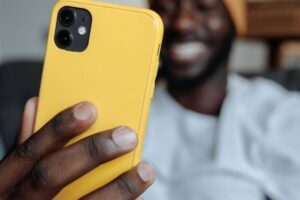Mano di uomo tiene cellulare con cover gialla