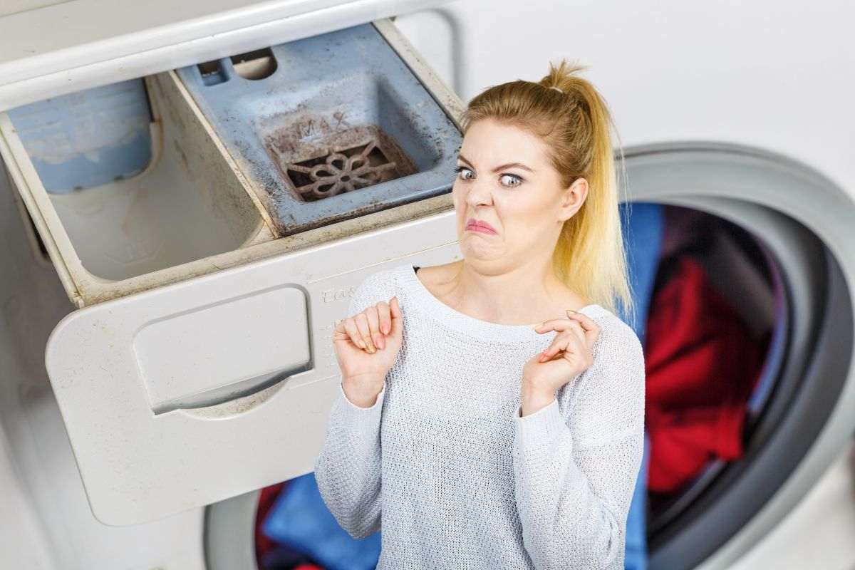 muffa cassetto lavatrice e donna disgustata