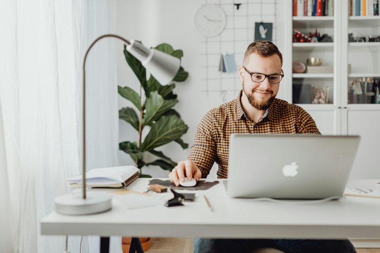uomo che sorride seduto davanti al computer