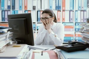 donna disperata seduta davanti ad un computer dentro ad un ufficio